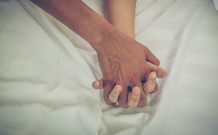 mani che si stringono tra uomo e donna su letto